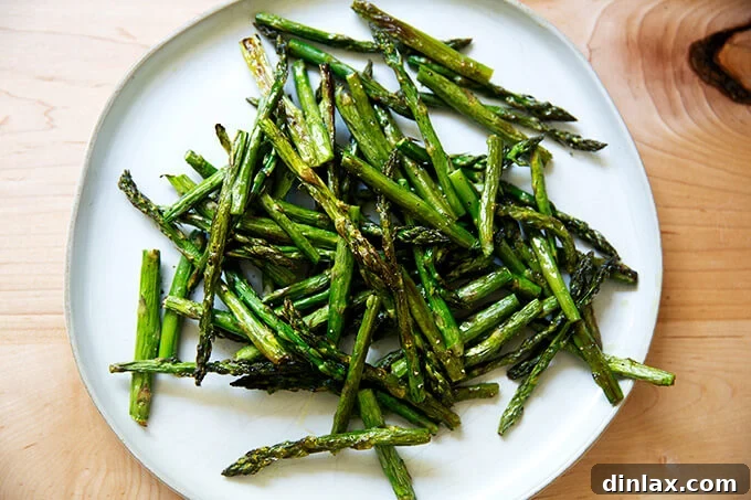 Effortless Balsamic Parmesan Roasted Asparagus 8 Freshly roasted asparagus spears neatly arranged on a white serving platter, awaiting the final toppings.