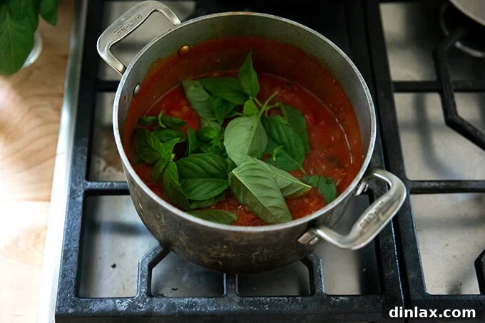 Pantry-Perfect Tomato Sauce in Minutes 9 A pot of tomato sauce simmering stove top with fresh basil added.
