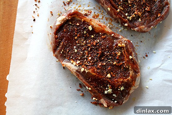 Raw Grass-Fed Ribeye Steaks Two raw, marbelized grass-fed ribeye steaks seasoned with salt and pepper, ready for grilling.