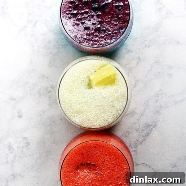 A trio of vibrant paloma slushies, garnished with fresh fruit.