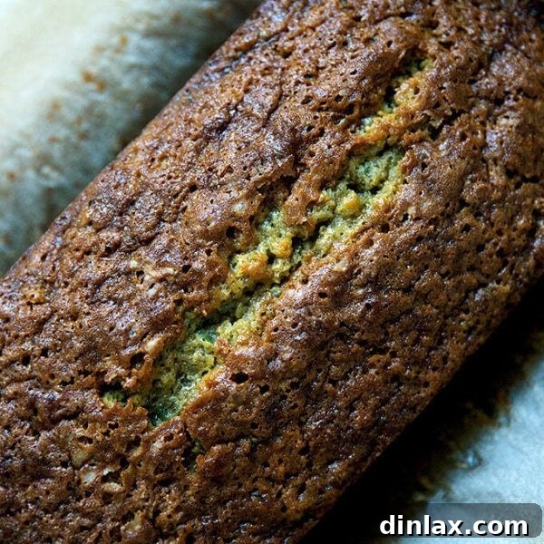 A top-down view of a golden-brown, baked zucchini bread with a slightly crisp crust.