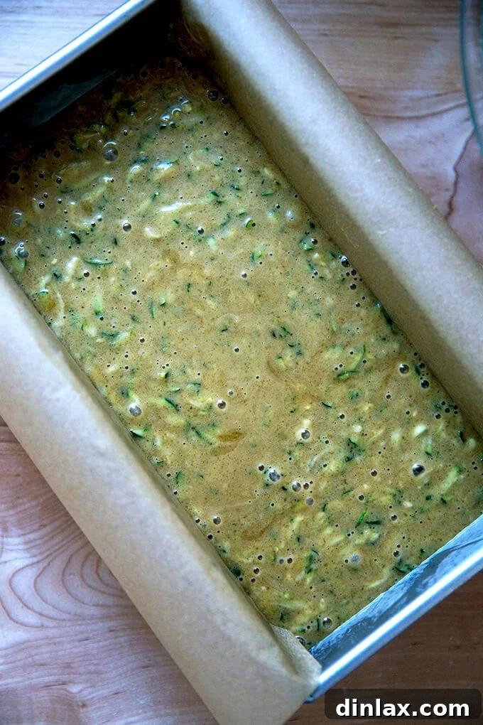 Decadently Moist Zucchini Bread Bliss 8 A metal loaf pan perfectly filled with raw zucchini bread batter, ready for baking in the oven.