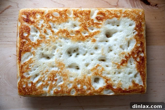 A parbaked Detroit-style pizza crust cooling upside down.