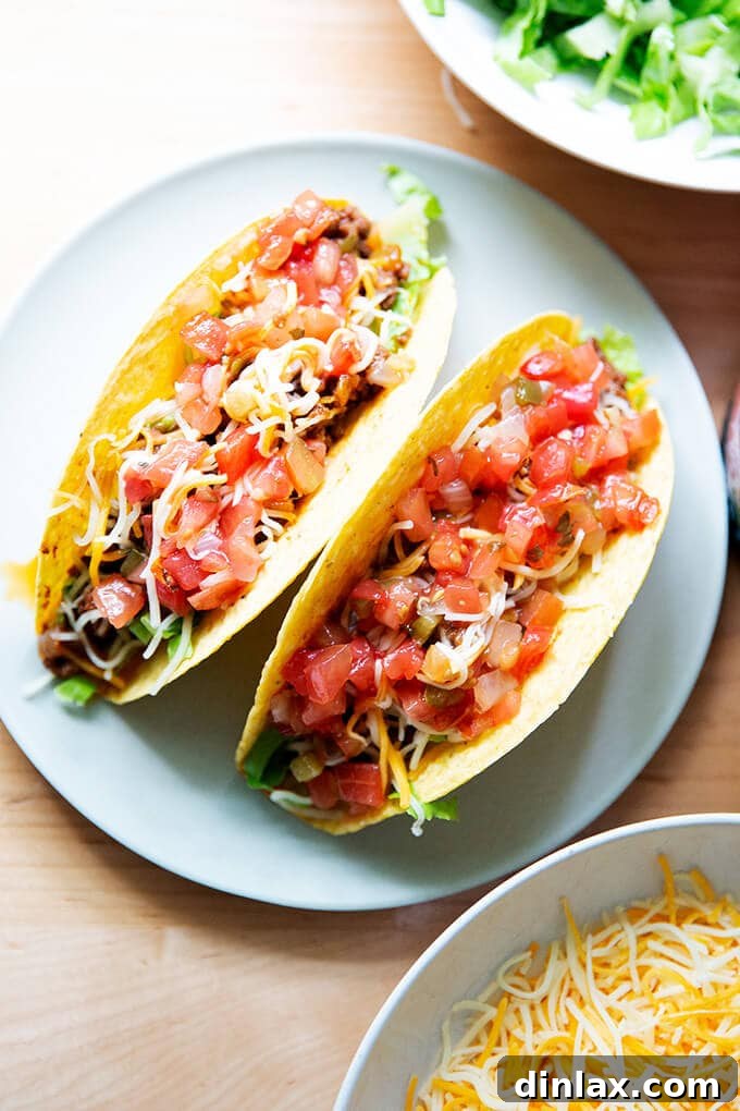 Two hard shell tacos filled with taco meat, cheese, and salsa on a plate, perfectly arranged for a simple and delicious meal.