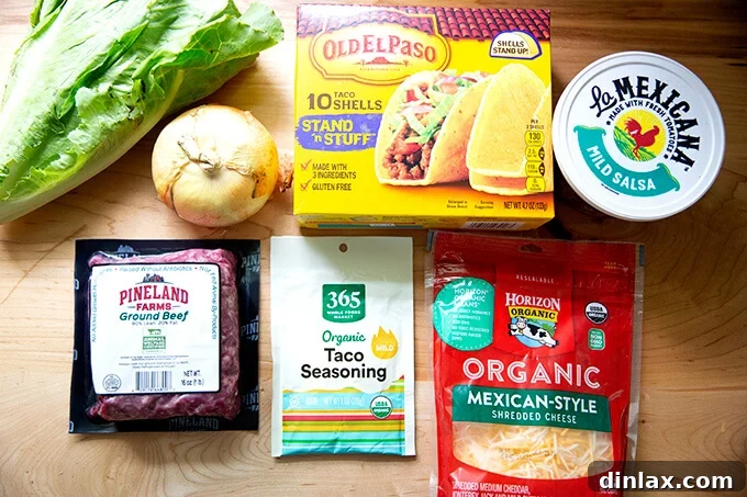 A selection of fresh ingredients laid out on a wooden cutting board, including ground beef, a whole onion, a packet of taco seasoning, and vibrant toppings, all ready to create truly simple tacos.