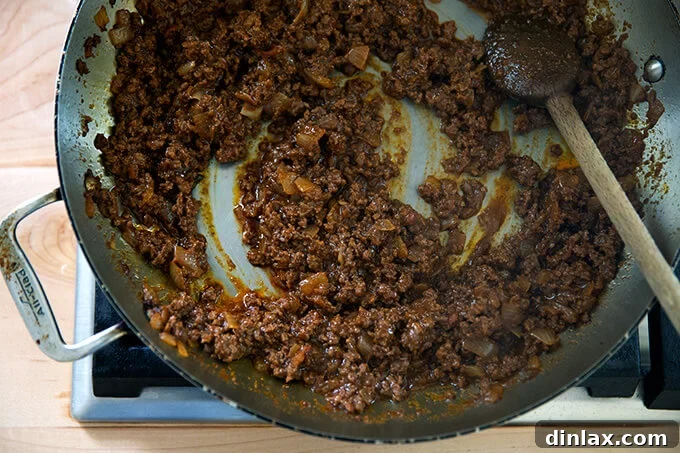 Perfectly simmered taco meat in a skillet, with much of the liquid reduced and the mixture looking thick and luscious, indicating it's ready for serving.