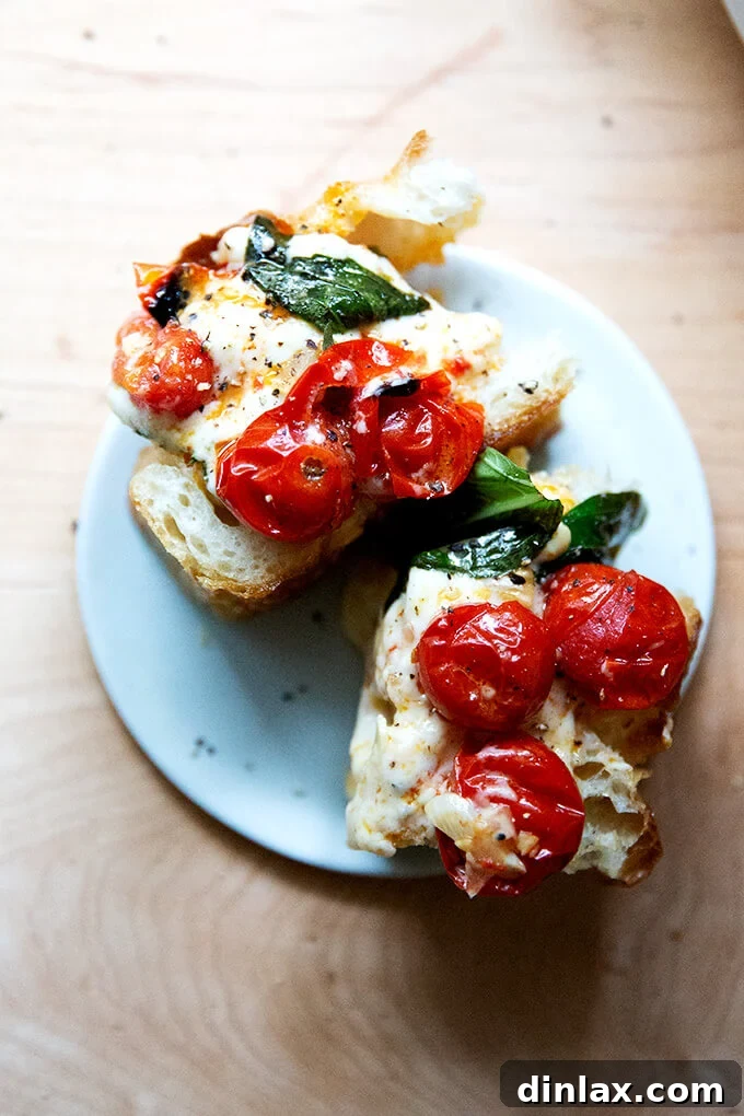Warm Feta & Burst Tomato Bake 13 A plate of two slices of focaccia topped with baked feta and tomatoes.