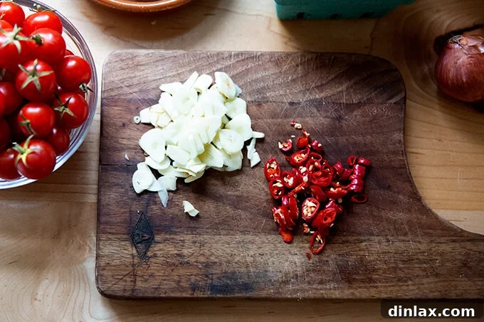 Warm Feta & Burst Tomato Bake 4 Sliced garlic and chilies on a cutting board.