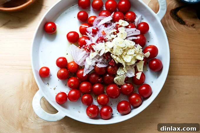 Warm Feta & Burst Tomato Bake 6 A baking dish filled with tomatoes, shallots, and sliced garlic.