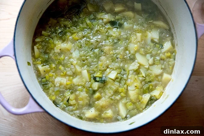 A large soup pot of potato leek soup, potatoes cooked and ready for puréeing.