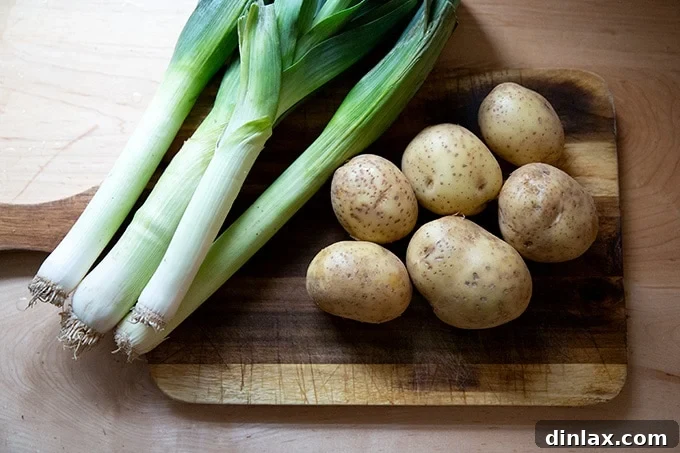 Leeks and potatoes on a cutting board, ready for preparation.