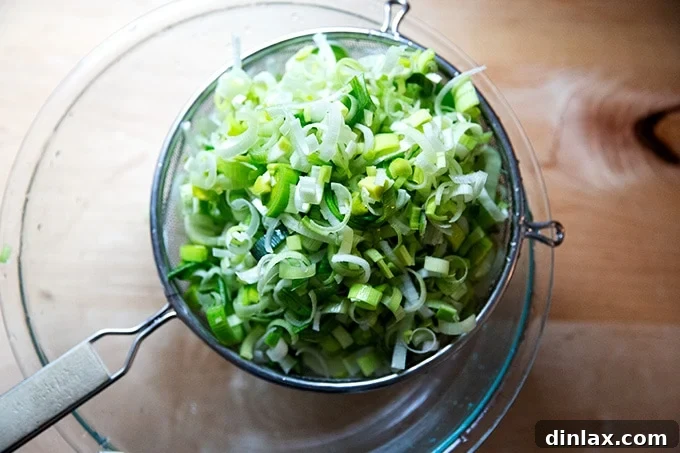 Cleaned leeks being scooped from water into a sieve.
