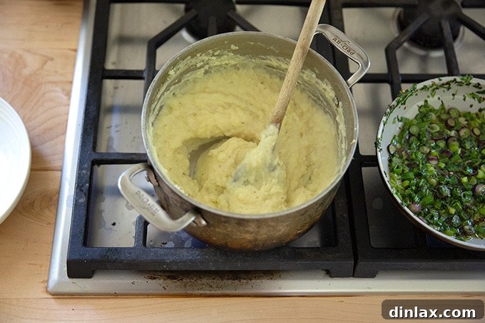 A pot of creamy, mashed potatoes on the stovetop after the final butter addition, showcasing their smooth texture.