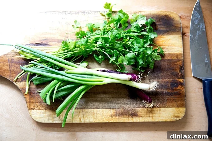 Fresh scallions and cilantro on a cutting board, ready for chopping to make the herby garnish.