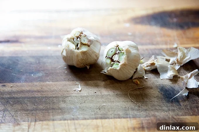 Two heads of garlic with their tops trimmed off, ready to be prepared for roasting.