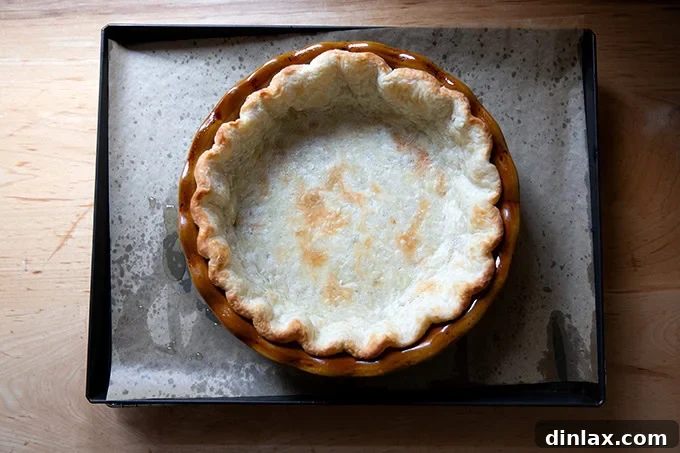 A parbaked pie crust on a parchment-lined sheet pan.
