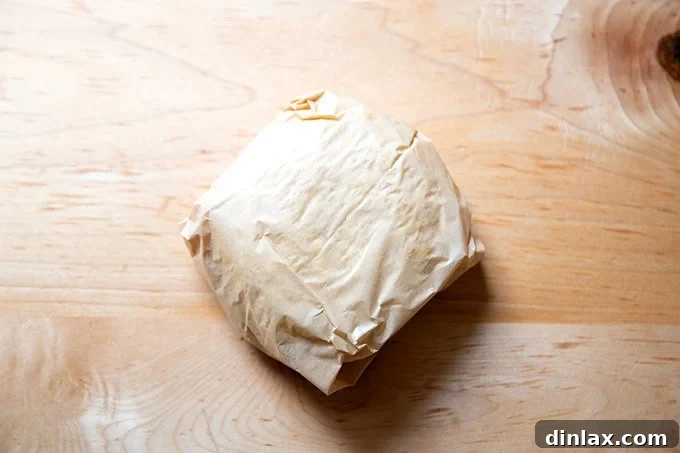 A round of pie dough wrapped in parchment paper.