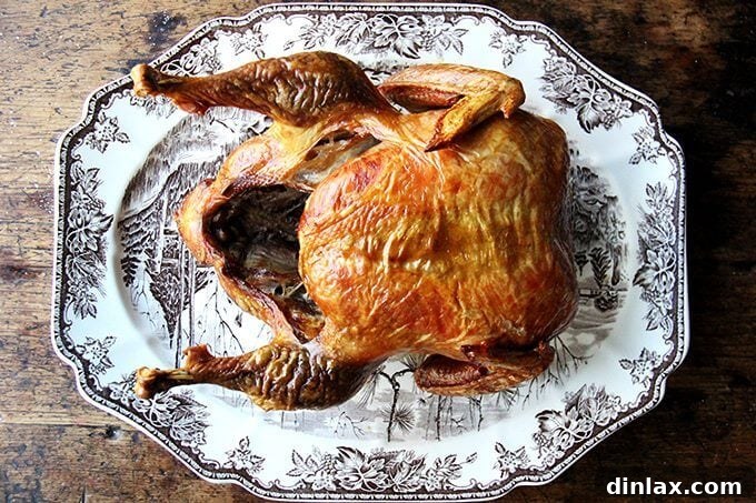 A golden-brown roasted turkey, beautifully carved and arranged on a platter with herbs.