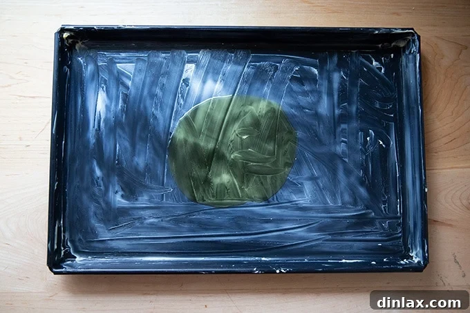 A baking sheet pan, meticulously prepared with a layer of butter followed by a generous pool of olive oil.