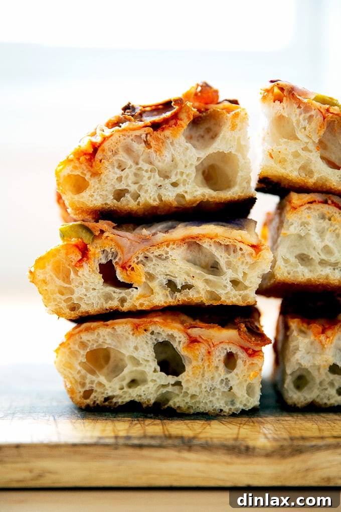 A beautiful stack of golden, square-cut Sicilian-style pizza slices, ready to be served.