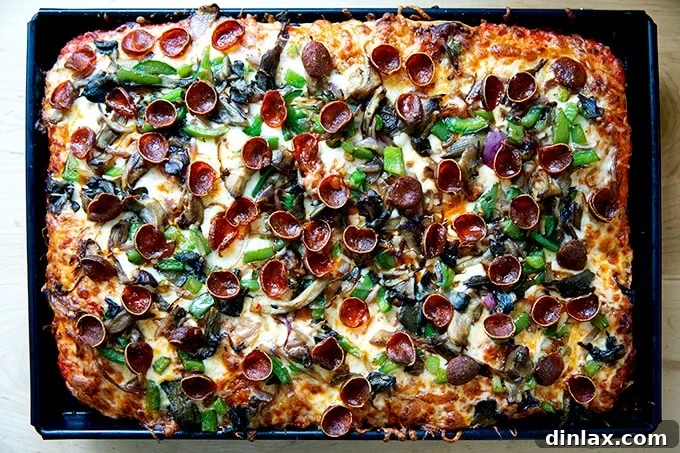 A Sicilian-style pizza, featuring a delicious combination of sautéed vegetables and pepperoni, still in its baking pan.