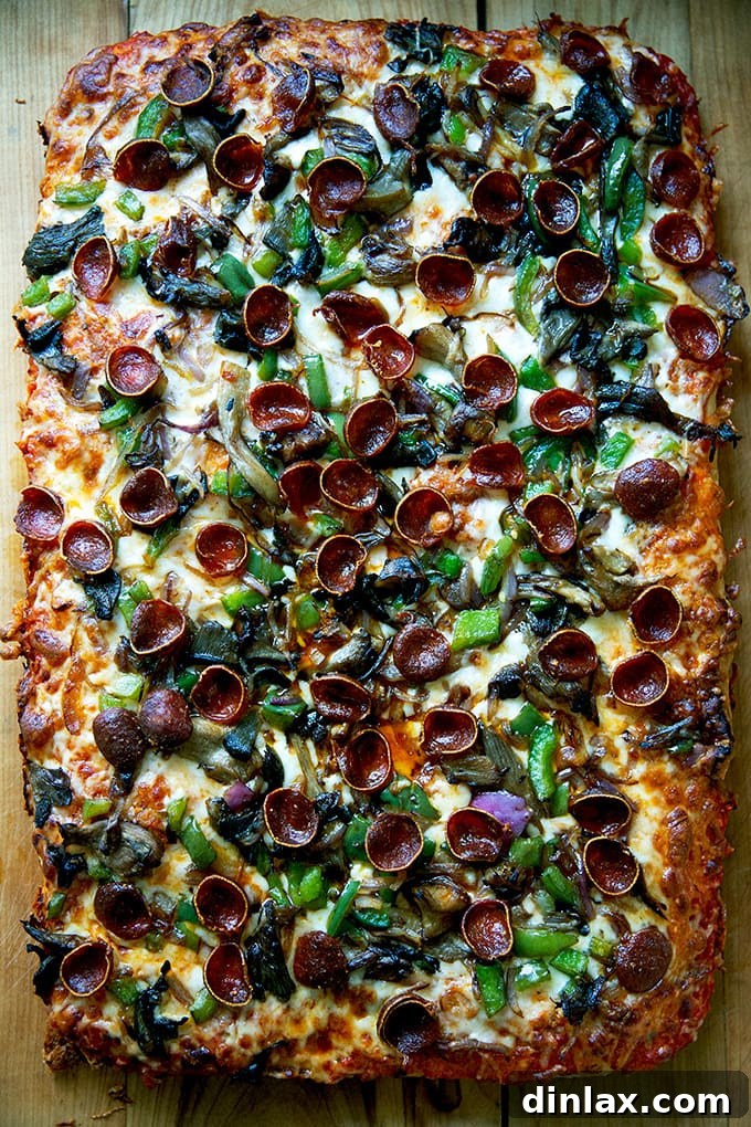 A freshly baked Sicilian-style pizza, showcasing its golden crust and melted toppings, presented on a cutting board.