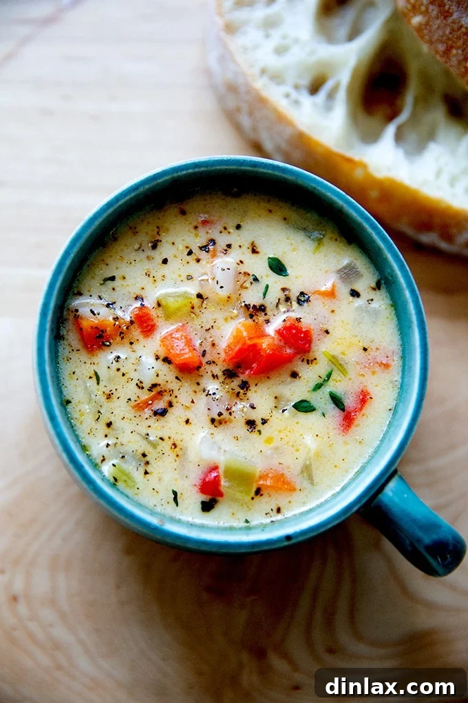 A steaming bowl of rich Vermont Cheddar Cheese and Beer Soup, garnished with fresh herbs, ready to be enjoyed.