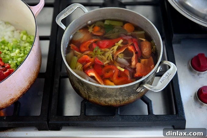 A clear, golden vegetable stock simmering in a pot on the stovetop, highlighting the fresh ingredients used.