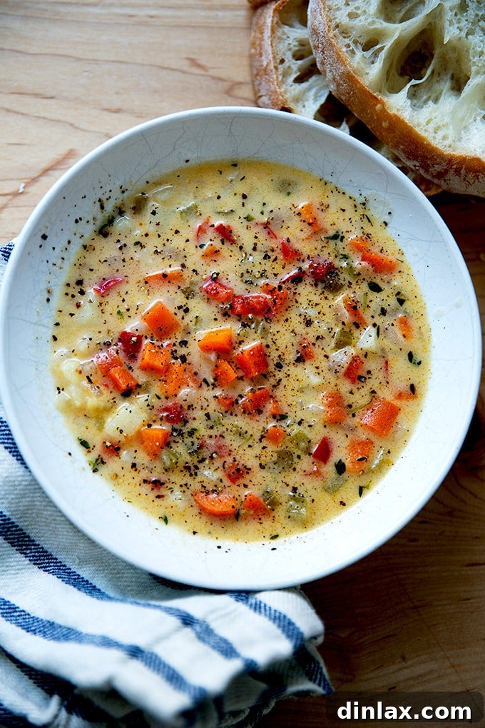 A cozy, inviting bowl of Vermont Cheddar Cheese Soup, steaming gently, with a side of crusty bread, promising comfort.