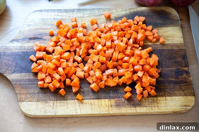Freshly diced carrots, uniformly cut and ready for cooking, displayed on a clean cutting board.