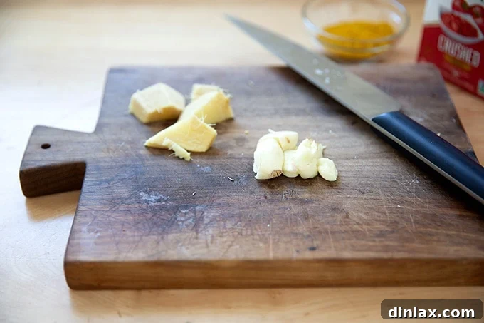 Effortless Butter Chicken and Chickpeas Instant Pot or Stovetop 4 Fresh ginger and garlic cloves resting on a wooden cutting board, ready for mincing.