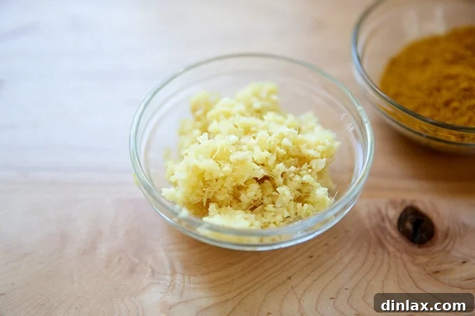 Effortless Butter Chicken and Chickpeas Instant Pot or Stovetop 5 A small white bowl filled with finely minced garlic and ginger, prepared for cooking.