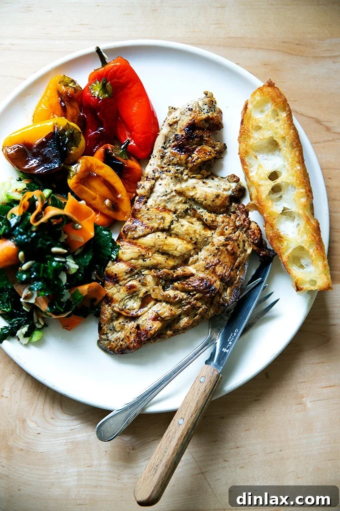 Simply Irresistible Grilled Chicken Breasts 2 A perfectly grilled, juicy chicken breast served on a plate with fresh bread, vibrant peppers, and a crisp green salad.