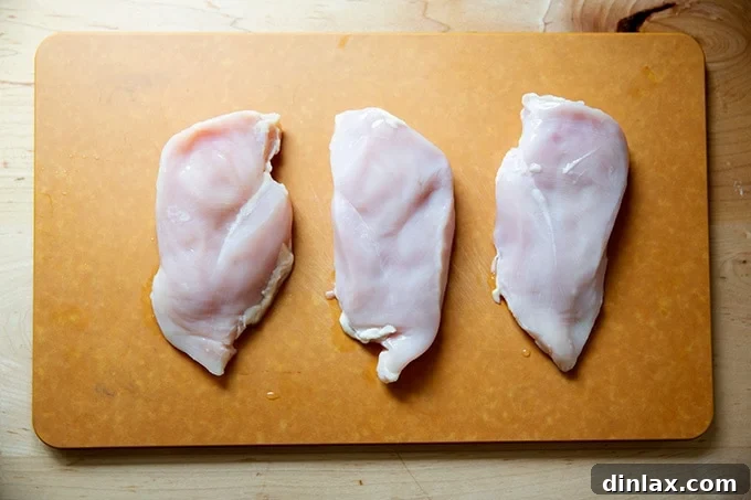 Simply Irresistible Grilled Chicken Breasts 3 Three raw chicken breasts ready for pounding on a cutting board.