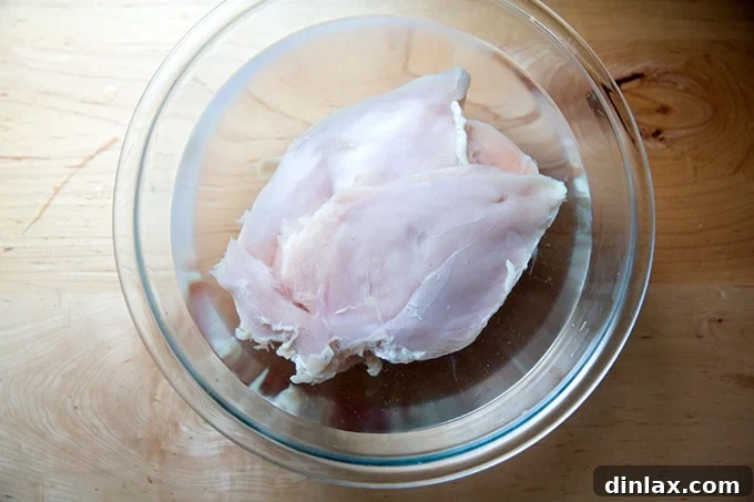 Simply Irresistible Grilled Chicken Breasts 7 Chicken breasts fully submerged in the brining solution within a large glass bowl, illustrating the brining process.