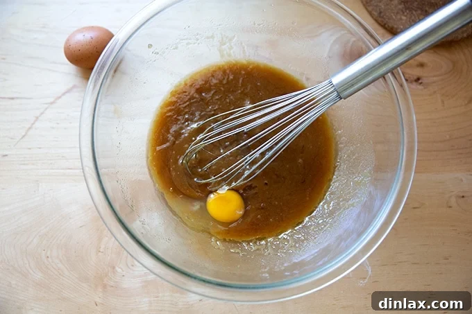 One large egg cracked into the peanut butter cookie dough batter, being gently whisked to combine with the wet ingredients.