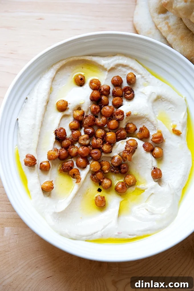 A beautifully presented platter of homemade hummus generously topped with golden, crispy chickpeas and a drizzle of olive oil.