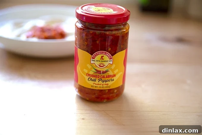 A jar of vibrant red Calabrian Chili Paste, an optional garnish for adding a spicy kick to homemade hummus.