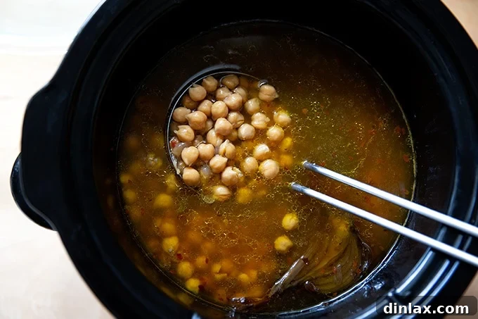 A crockpot filled with freshly cooked, tender chickpeas, ready for making hummus.