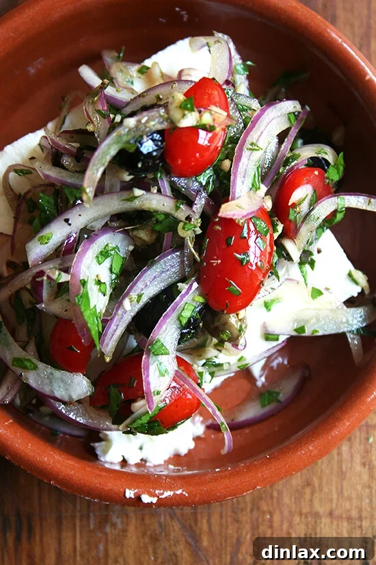 Block of feta cheese, ready for the oven, topped with fresh ingredients