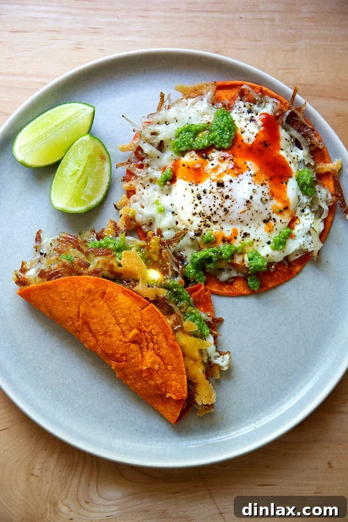 A vibrant plate of crispy potato, egg, and cheese tacos, garnished with fresh lime and hot sauce.