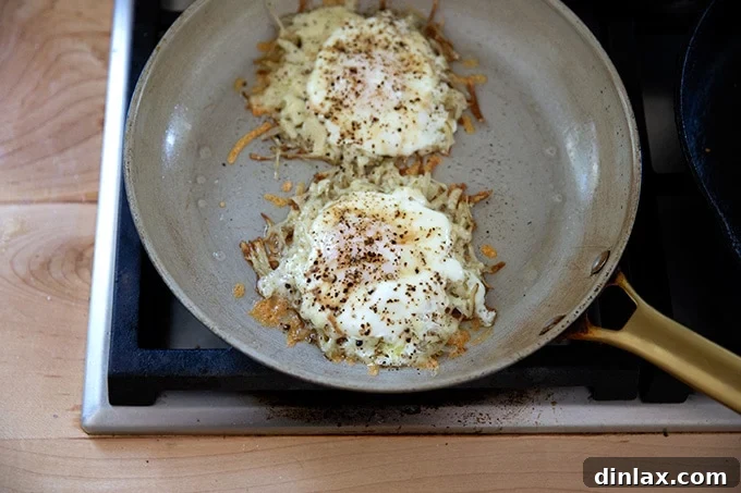 An uncovered skillet revealing two perfectly cooked crispy potato, egg, and cheese portions, ready to be served.