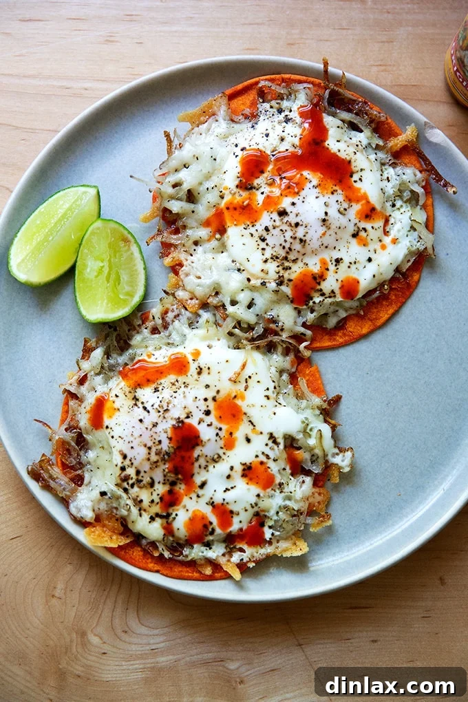 A plate featuring two crispy potato, egg, and cheese tacos, artfully garnished with fresh lime wedges and a swirl of hot sauce.