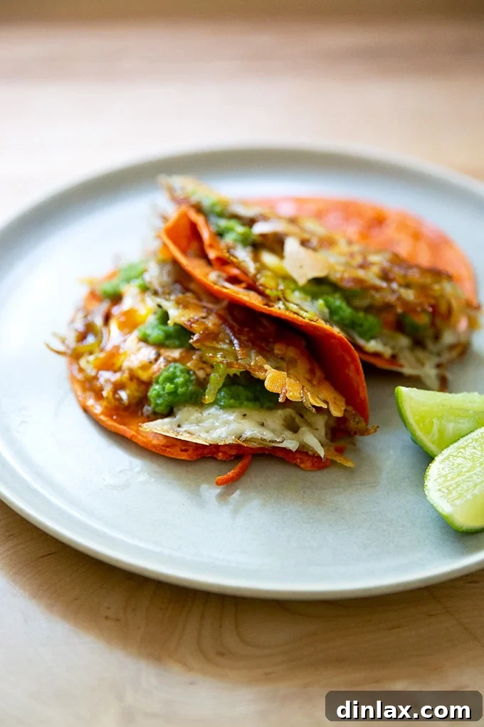 A beautifully composed plate of two crispy potato, egg, and cheese tacos, showcasing their delicious layers and readiness to be savored.