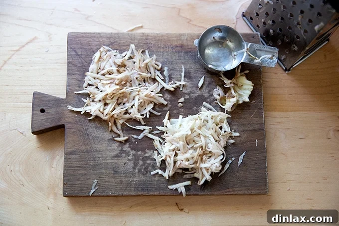 Two separate, lightly packed piles of finely grated potato resting on a cutting board, ready for cooking.