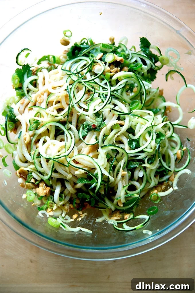 Refreshing Peanut Noodle Salad with Crisp Cucumbers 14 A large mixing bowl containing a freshly tossed cold peanut noodle salad with cucumbers, scallions, and peanuts, showing the vibrant mix of ingredients.