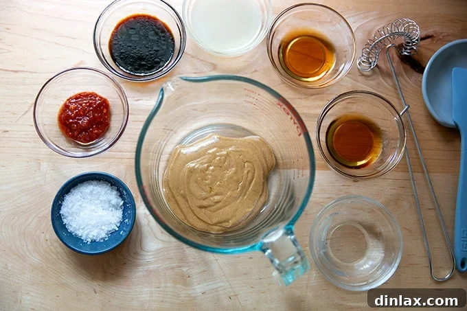 Refreshing Peanut Noodle Salad with Crisp Cucumbers 3 A collection of ingredients for the peanut dressing, including a bowl of peanut butter, lime, soy sauce, sesame oil, and maple syrup, perfectly arranged on a light surface.