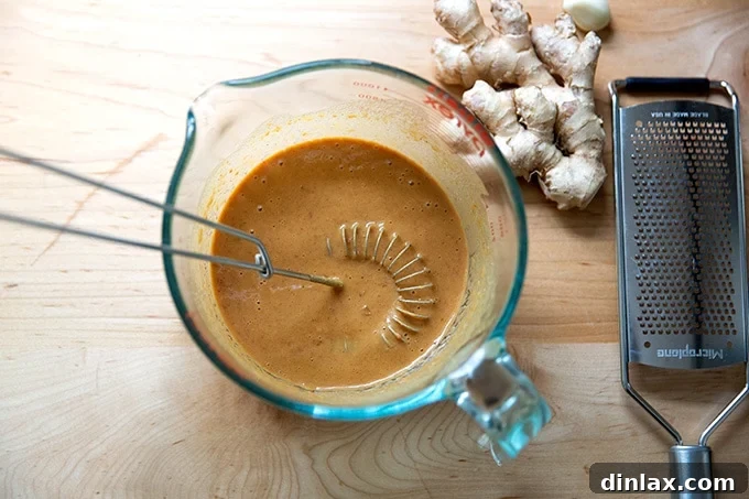 Refreshing Peanut Noodle Salad with Crisp Cucumbers 4 The peanut dressing in a bowl, flanked by freshly grated garlic and ginger, showcasing the key aromatic additions.