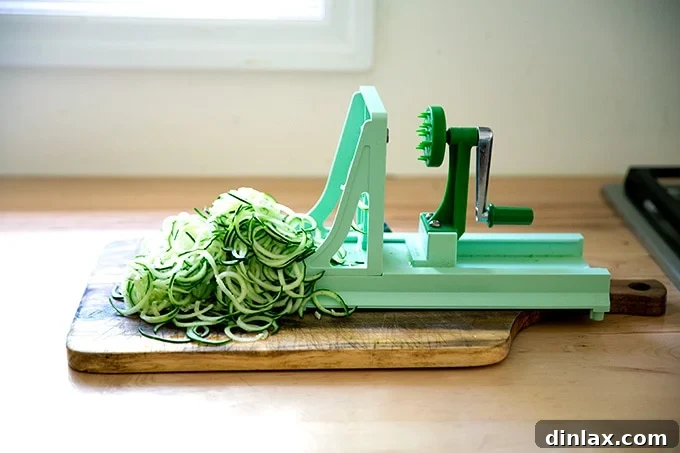 Refreshing Peanut Noodle Salad with Crisp Cucumbers 7 A turning slicer efficiently spiralizing a fresh cucumber on a clean countertop, producing delicate vegetable ribbons for the salad.