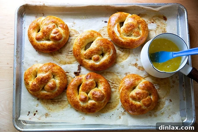 Pillowy Soft Pretzels Made Simple 25 Just-baked soft pretzels on a sheet pan being brushed with melted butter.